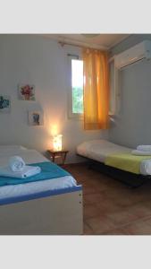 two beds in a room with a window at Villa Luminosa Kyra Panagia in Kyra Panagia