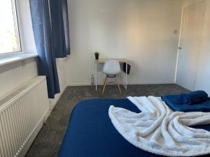 una stanza con un letto con un tappeto blu e una sedia di Lovely 3 Bedroom Home Heathrow Airport a Stanwell