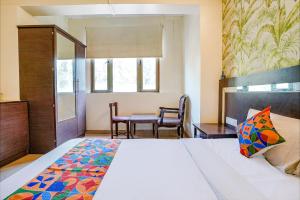 a bedroom with a bed and a table with chairs at FabHotel Gargi Deluxe in Pune