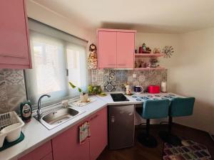 a small kitchen with pink cabinets and a sink at Villa Antoaneta in Panagia
