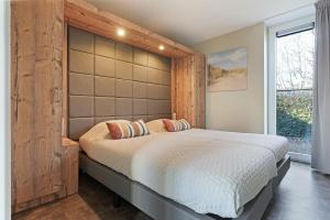 a bedroom with a large bed with a large padded headboard at Oude Nieuwlandseweg 33 - Ouddorp - Villa Mastlo met 2 jacuzzi's - NOT FOR COMPANIES in Ouddorp +29 photos