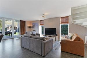 a living room with two couches and a television at Oude Nieuwlandseweg 33 - Ouddorp - Villa Mastlo met 2 jacuzzi's - NOT FOR COMPANIES in Ouddorp