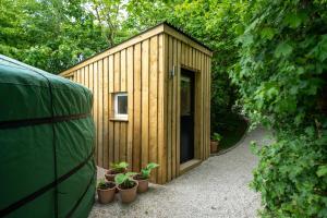 a wooden shed with potted plants in front of it at Yurt with Hot Tub near Hartington, Peak District in Buxton