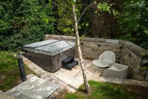 a stone wall with a hot tub and a chair at Yurt with Hot Tub near Hartington, Peak District in Buxton