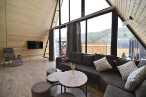 a living room with a couch and tables and windows at Avra Resort Tsaghkadzor in Tsaghkadzor