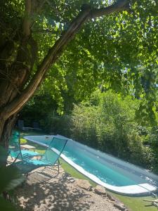 a swimming pool with two chairs and a tree at Chez maman in Bassan