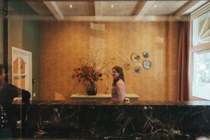 アムステルダムにあるHotel Asterisk, a family run hotelの部屋の窓口に立つ女