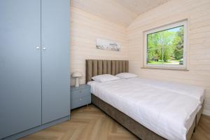 a bedroom with a white bed and a window at Boogie House domki nad morzem in Jarosławiec +35 photos