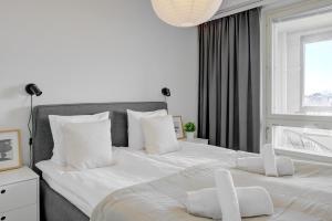 a bedroom with two beds with white pillows and a window at Modern and Stylish 1BR with Balcony and City View in Helsinki