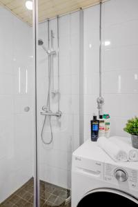 a bathroom with a shower and a washing machine at Modern and Stylish 1BR with Balcony and City View in Helsinki +37 photos