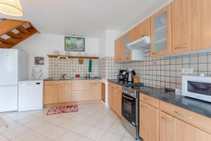 a large kitchen with wooden cabinets and a microwave at Gte Elaïa Class 3 Au Coeur Du Pays in Guiche +15 photos