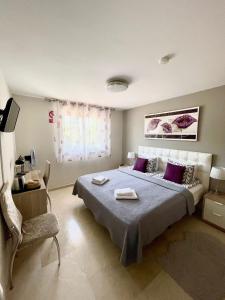 a bedroom with a bed with purple pillows and a chair at Marbella Deluxe Rooms in Royal Cabopino Townhouse in Marbella