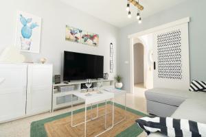 a white living room with a tv and a couch at Casa Nao Santiago - Sanlúcar de Barrameda - Centro Playa in Sanlúcar de Barrameda
