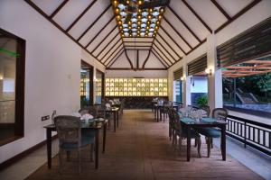 a dining room with tables and chairs and windows at Reen Resorts Aanavilasam Plantation Thekkady in Thekkady