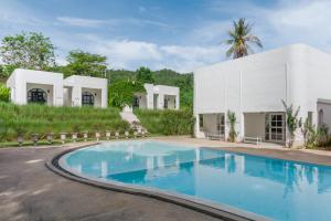 an exterior view of a white building with a swimming pool at Villa La Flora Kaeng Krachan in Kaeng Krachan