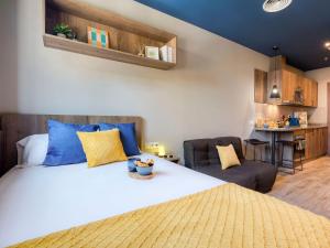 a bedroom with a large bed with blue and yellow pillows at Livensa Living Studios Valencia Marina Real Hotel-Apartamento in Valencia