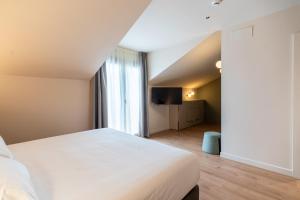a bedroom with a white bed and a large window at Hotel Los Pasiegos in Hoznayo