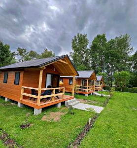 a row of log cabin homes in a field at Hotel Restorant Natyra Diber Camping in Podgorcë