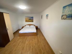 a bedroom with a bed and a wooden floor at Apartament A2 - EVIM in Mangalia +4 photos