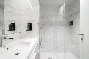 a white bathroom with a shower and a sink at Limehome Lisbon Defensores de Chaves in Lisbon +41 photos