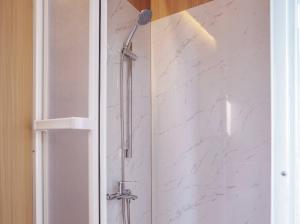 ein Bad mit einer Dusche und weißen Marmorwänden in der Unterkunft Mountain Silhouette Cottage 2 by Tiny Away in Jingmei + 6 Fotos