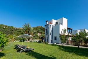 a house with an umbrella and a table and chairs at Villa Nimfea in Ialyssos