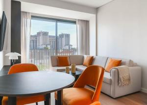 a living room with a couch and a table and chairs at Limehome Lisbon Defensores de Chaves in Lisbon