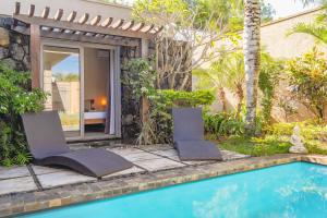 a pool with two chairs next to a house at Tropical Villa - 3 Bedrooms in the heart of Grand-Baie in Grand Baie