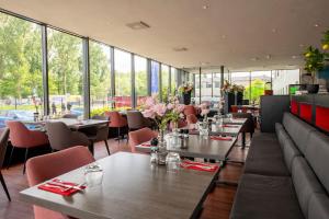 a restaurant with tables and chairs and windows at Bastion Hotel Zaandam in Zaandam