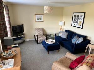 a living room with a blue couch and a tv at Gorgeous Dornoch apartment in Dornoch