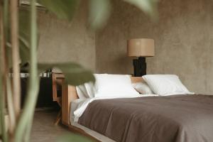 a bed with white pillows and a lamp in a room at The Iggy Hotel Seseh Studio 4 in Cemagi