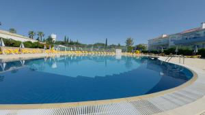a large swimming pool with chairs and a building at Villa Oasis Parque BY SWEET HOME in Portimão
