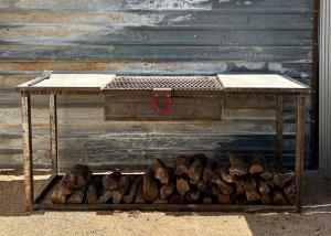a wooden table with a pile of wood next to a wall at Entire Private Boutique Motel w Courtyard and Sauna in Marfa