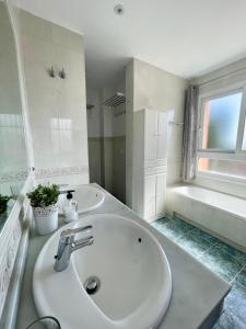 a white bathroom with a sink and a tub at Marbella Deluxe Rooms in Royal Cabopino Townhouse in Marbella