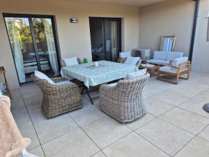 a patio with a table and wicker chairs at Appartement Neuf Grande Terrasse AGOSTA PLAGE in Albitreccia