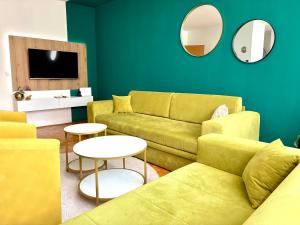a living room with yellow furniture and a green wall at Apartman Minja in Višegrad