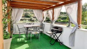 a balcony with a table and chairs on a green floor at Domo Marzellinu in Orosei