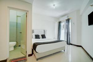 a white bedroom with a bed and a bathroom at Collection O near Terminal Pulo Gebang formerly Sentra Timur - Tower Sapphire in Jakarta