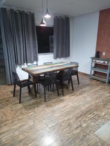 una mesa y sillas en una habitación con cortinas en Casa das Palmeiras 2, en Itanhaém