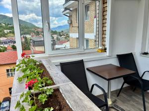 a table and chairs on a balcony with a window at Apartman Minja in Višegrad
