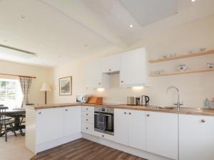 Una cocina con gabinetes blancos y una mesa. en South Cottage, en Glenelg