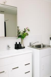 a white kitchen with a sink and a mirror at Little Luxe Retreat in Findon +14 photos
