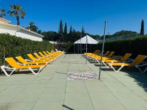 a row of yellow lounge chairs and an umbrella at Villa Oasis Parque BY SWEET HOME in Portimão