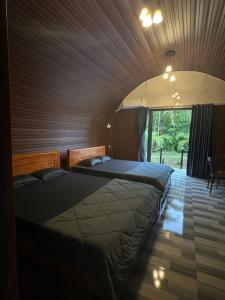 two beds in a room with a large window at Mây's Garden Villa in Tây Ninh
