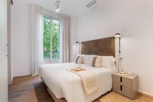 a white bedroom with a large bed and a window at Aspasios Rambla Catalunya Apartments in Barcelona