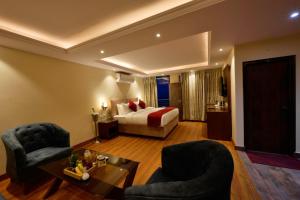a hotel room with a bed and two chairs and a table at Rajgriha Luxury Kasauli Stay in Kasauli