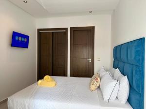 a bedroom with a white bed with a blue headboard at Chic & Bright Apartment in Kenitra +12 photos