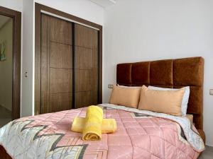 a bedroom with a bed with two yellow towels on it at Chic & Bright Apartment in Kenitra