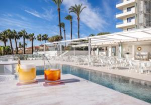 two drinks on a table next to a swimming pool at Hotel Ocean House Costa del Sol, Affiliated by Meliá in Torremolinos