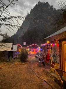 un groupe de bâtiments avec des lumières devant une montagne dans l'établissement Parvati hills Cottage, à Kasol